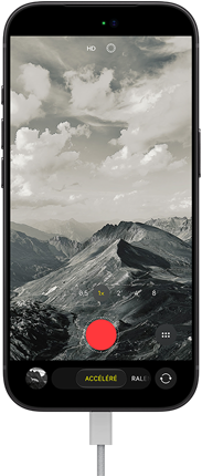 iPhone 18 Pro, face avant, affichant un paysage montagneux, avec le mode caméra incrusté en mode Accéléré, avec câble d’alimentation branché sur le port de charge