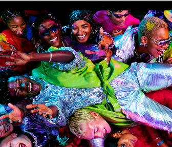MacBook Pro montrant une image colorée d’une personne se laissant transporter à bout de bras par une foule dans une fête, mettant en valeur le superbe écran Liquid Retina XDR